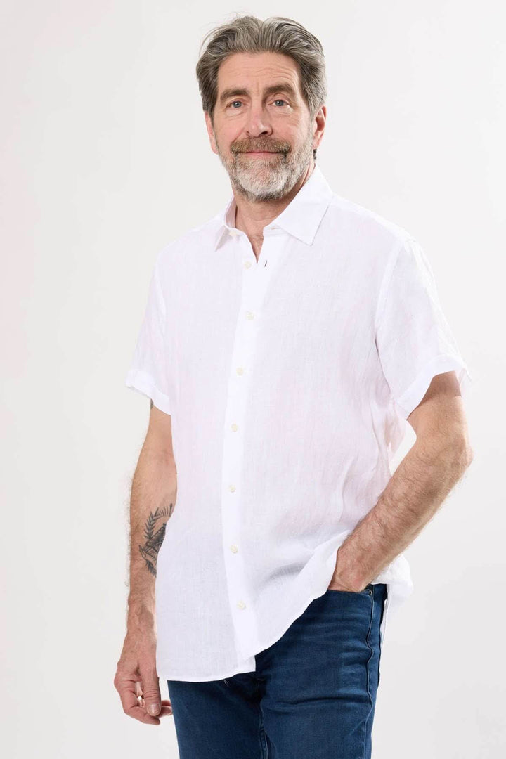 Chemise en lin blanche à manches courtes portée par un homme avec un sourire, parfaite pour l'été.