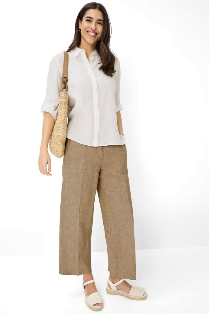 Femme portant une Chemise en lin VICKI blanche, manches trois-quarts, avec un sac en osier, idéale pour l&