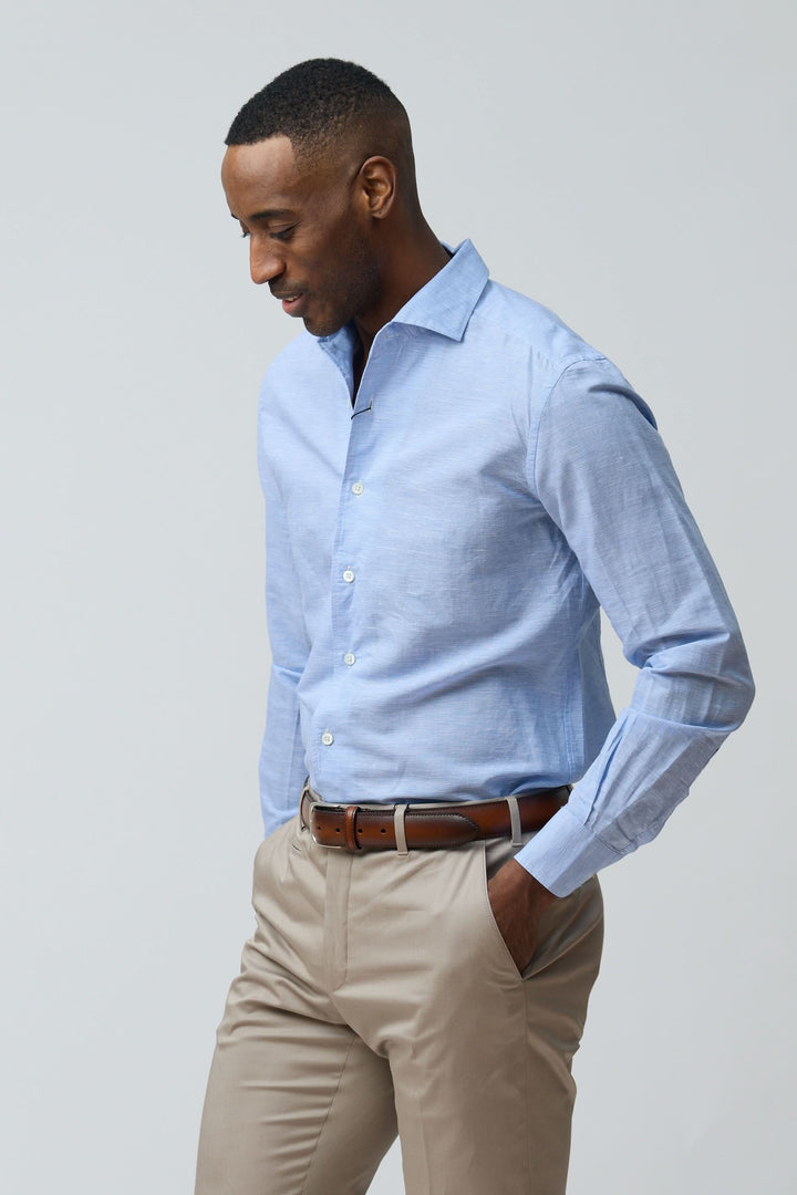 Homme portant une chemise en lin légère et raffinée, coupe ajustée, bleu clair, avec manches longues et col classique structuré.