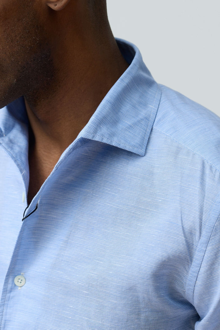 Homme portant une chemise en lin légère et raffinée, tissu bleu clair avec col structuré et fermeture boutonnée.