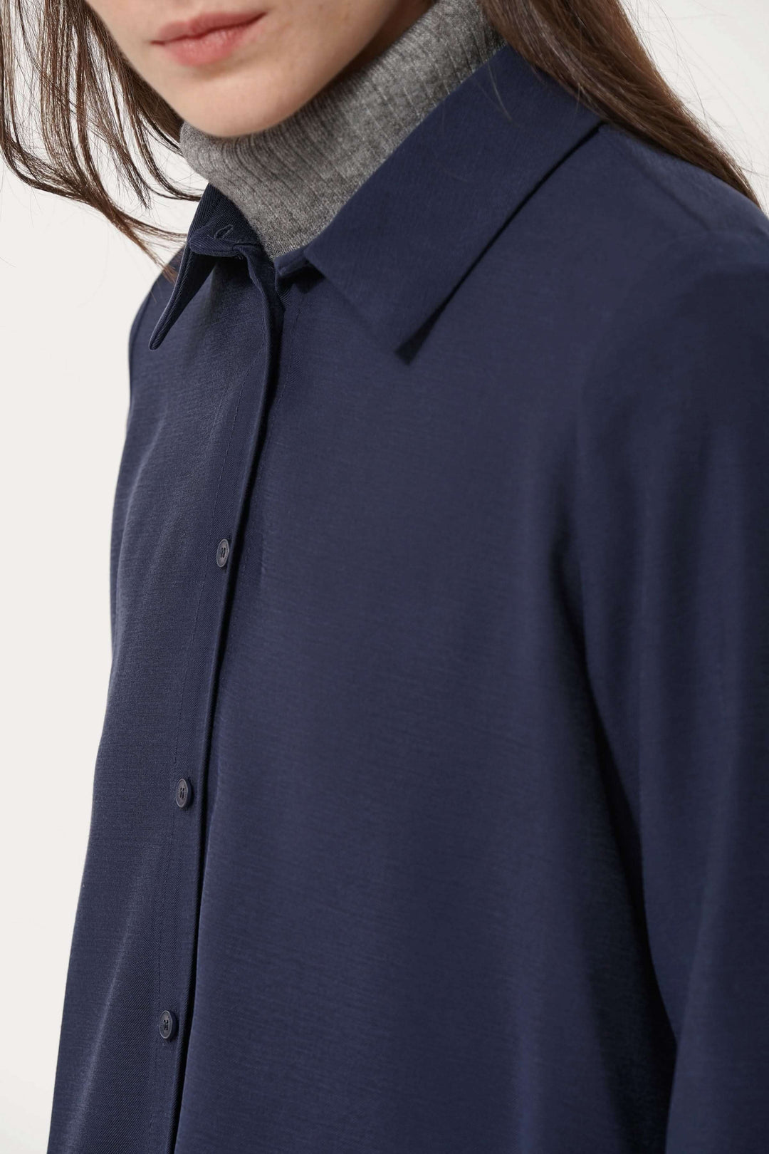 Chemise fluide élégante bleue marine, portée avec un col roulé gris pour un look raffiné.