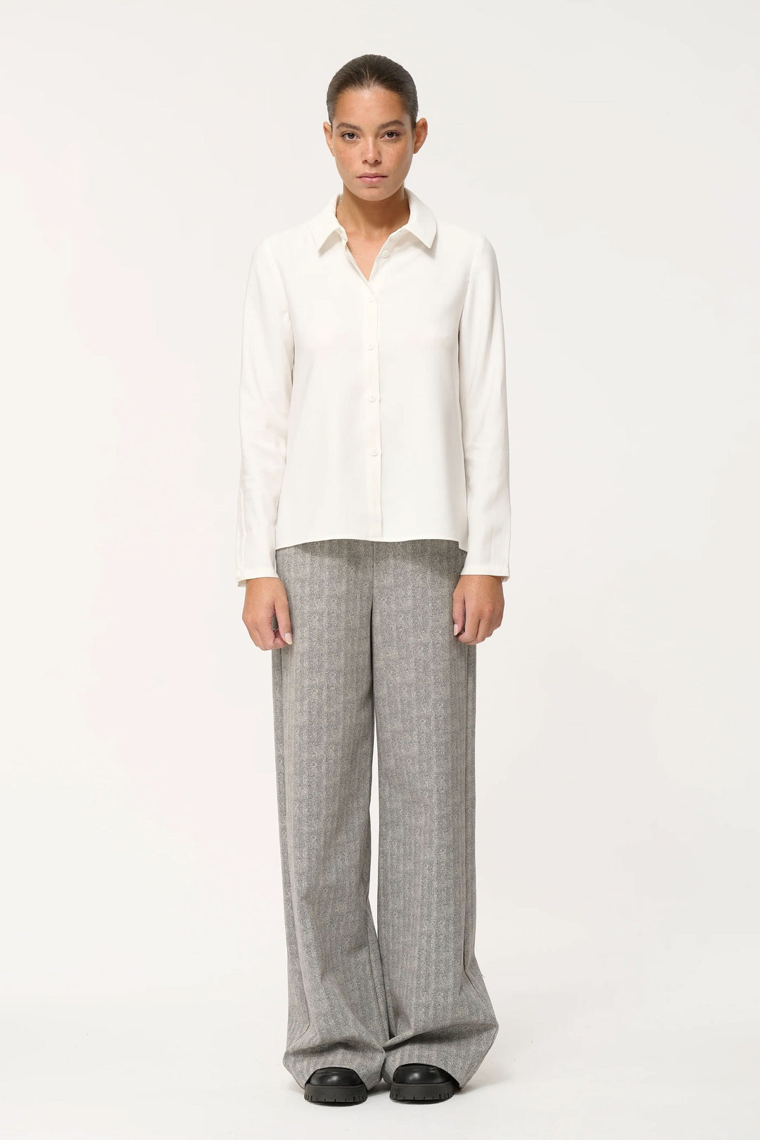 Chemise fluide blanche avec pantalon large rayé, un look élégant et confortable pour le quotidien.