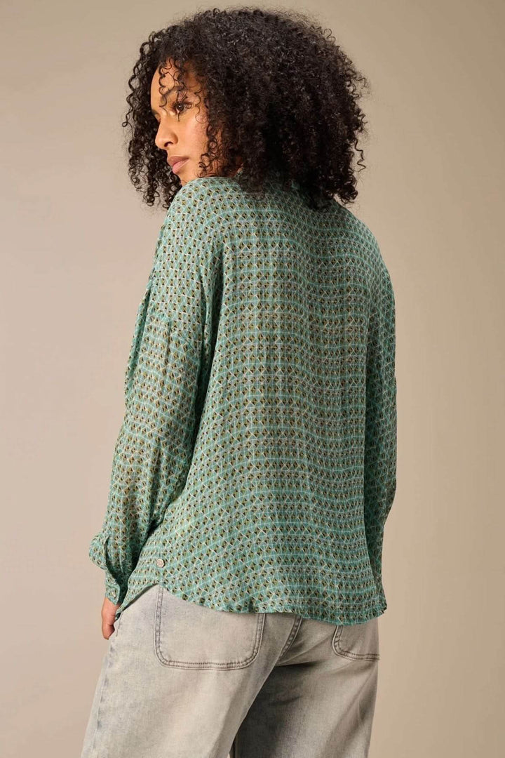 Personne portant une chemise fluide imprimé géométrique avec coupe décontractée, vue de dos, couleur verte et col classique.