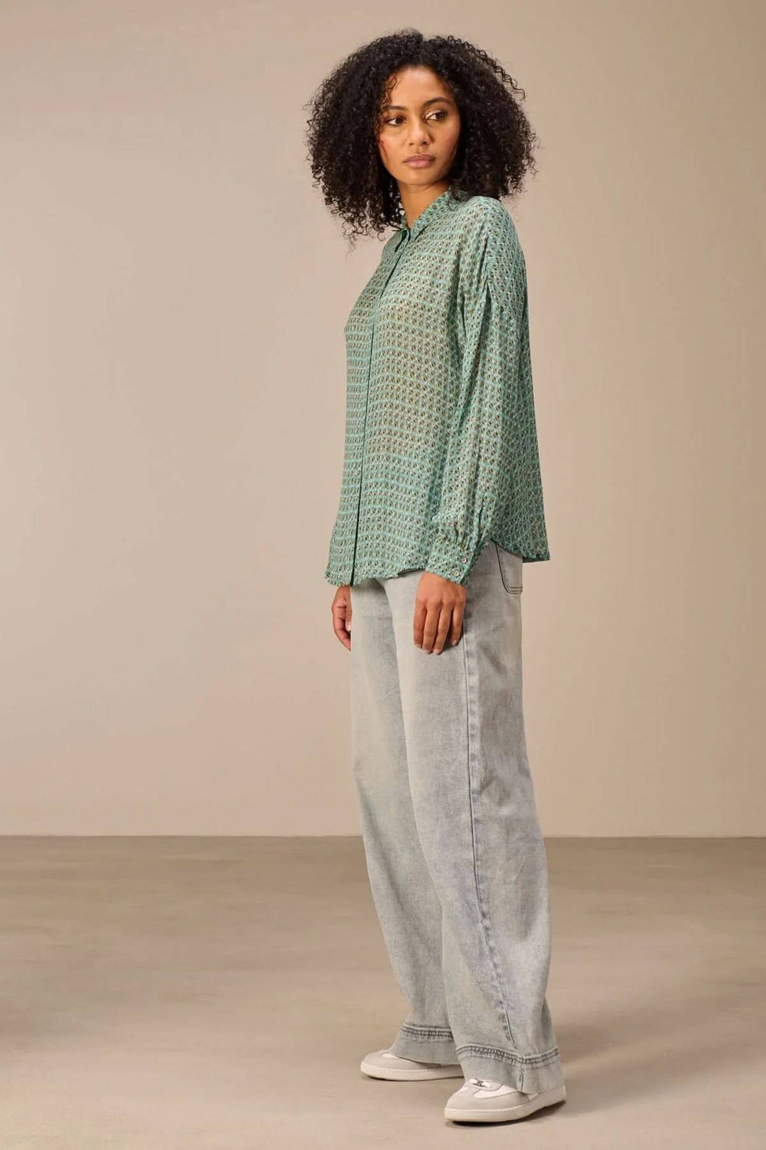 Chemise fluide imprimé à motifs géométriques raffinés, coupe décontractée, col classique et patte de boutonnage, portée avec un jean.