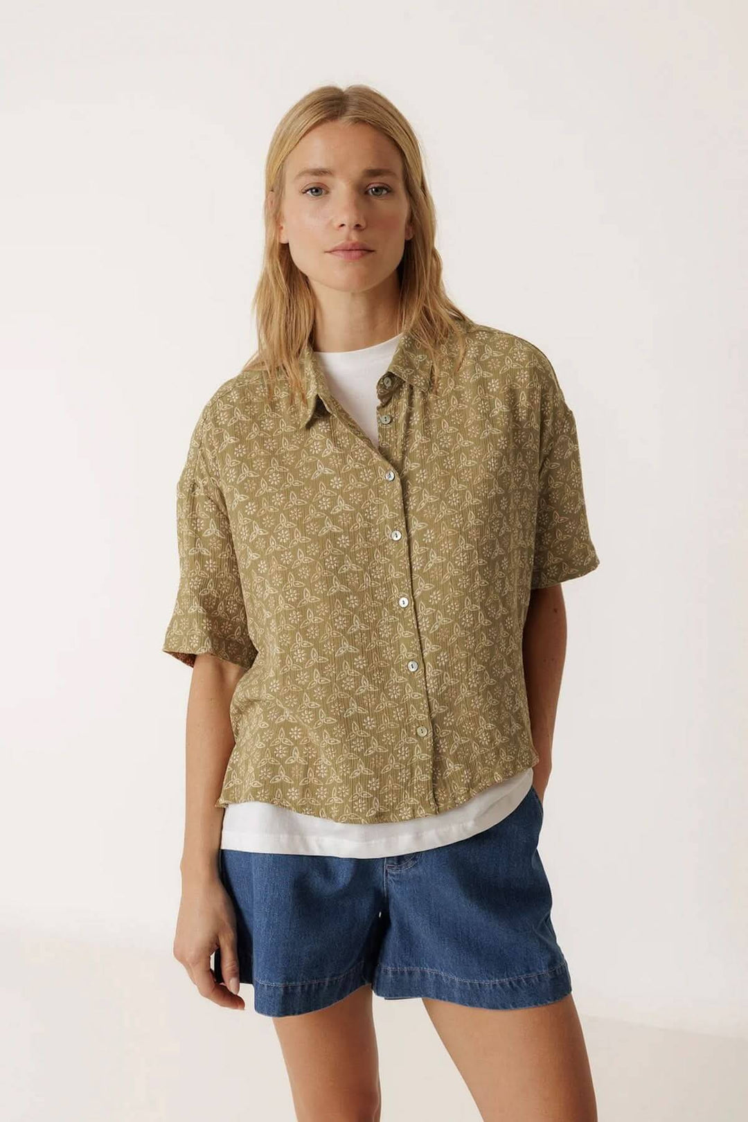 Chemise fluide imprimée à manches courtes avec imprimé délicat, col classique et manches courtes, portée par une femme.