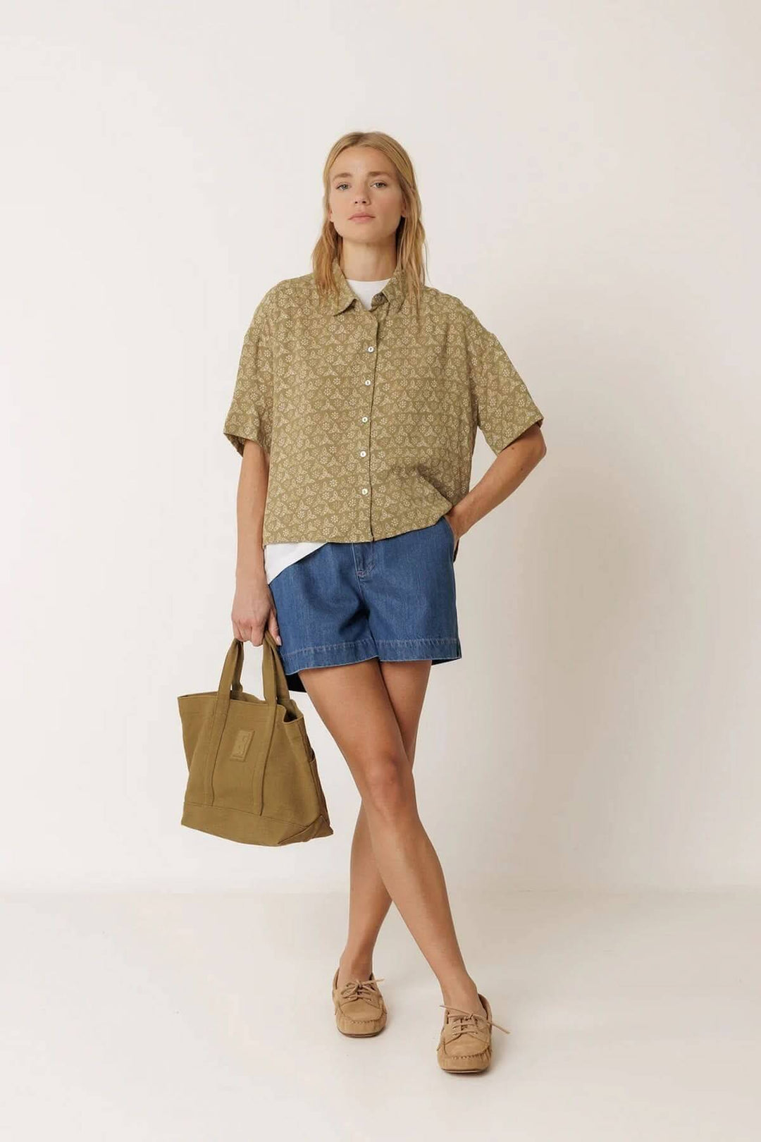 Femme portant une chemise fluide imprimée à manches courtes avec un short en jean et un sac à main, illustrant un style décontracté.