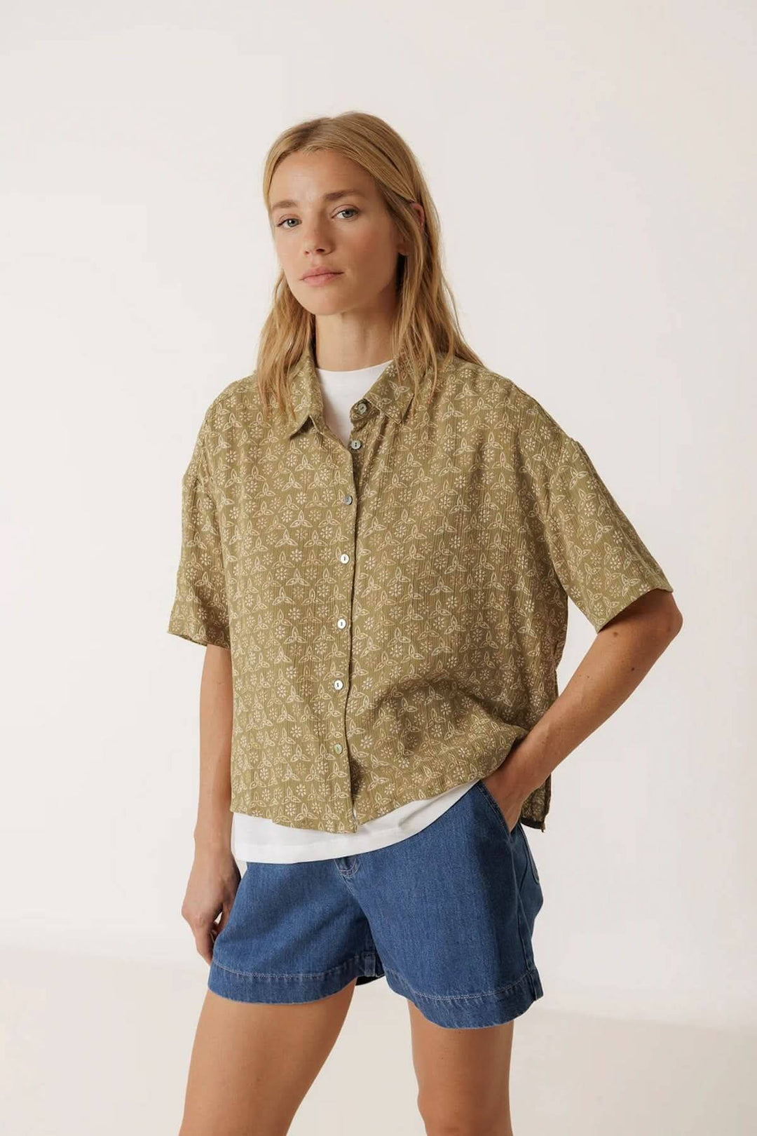 Femme portant une chemise fluide imprimée à manches courtes, style décontracté, col classique, sur fond neutre.