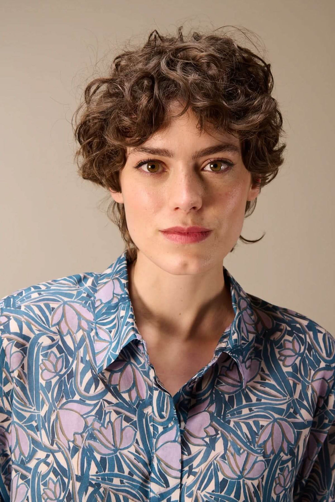 Femme portant une chemise fluide à manches trois-quarts avec imprimé floral élégant et coloré.