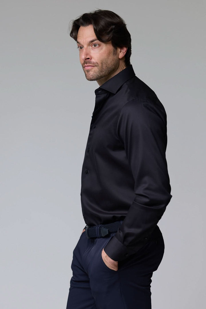 Homme portant une chemise habillée satinée noire avec coupe ajustée et col élégant pour un look sophistiqué et moderne.