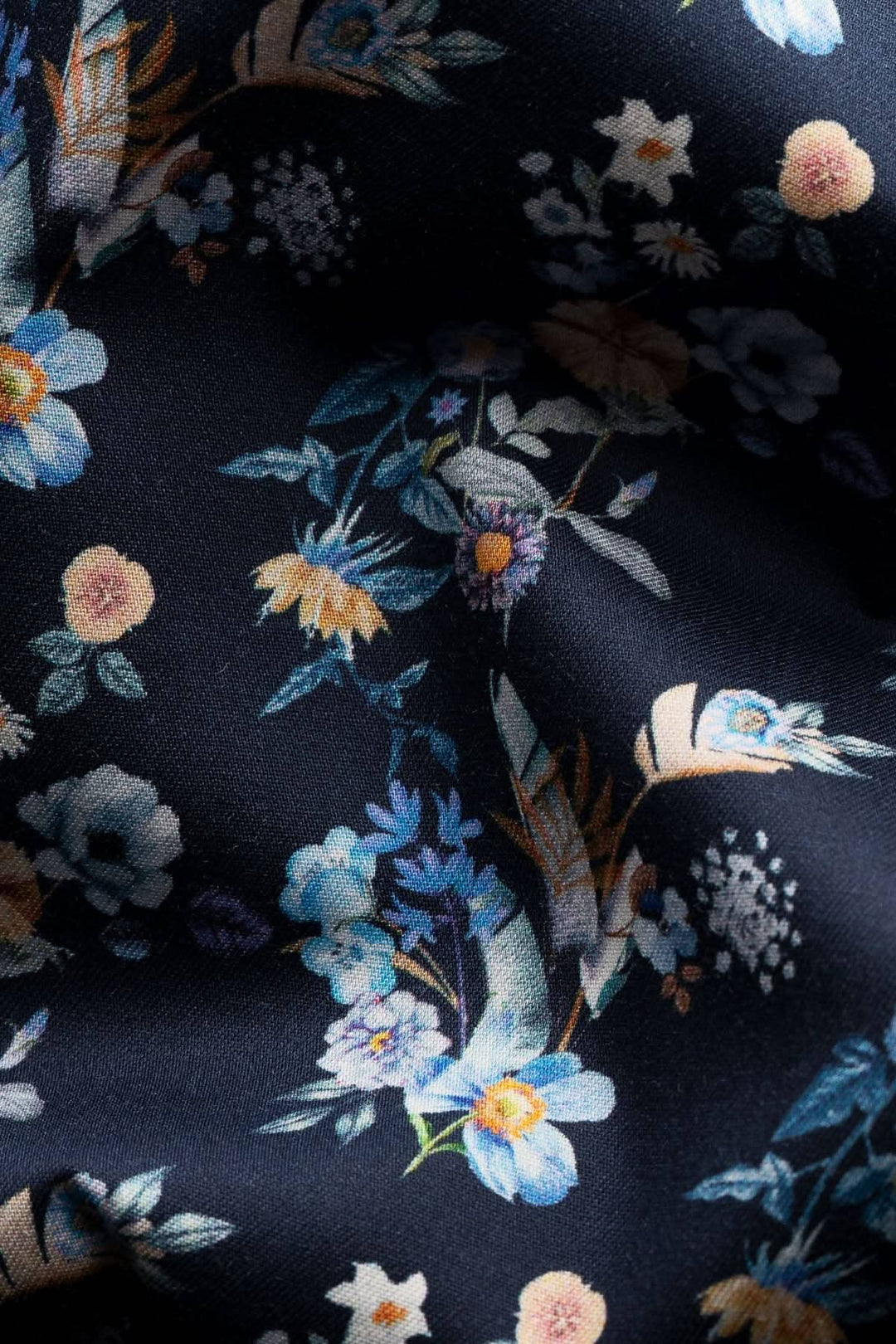 Imprimé de fleurs sur tissu noir, motifs colorés, idéal pour des vêtements élégants.