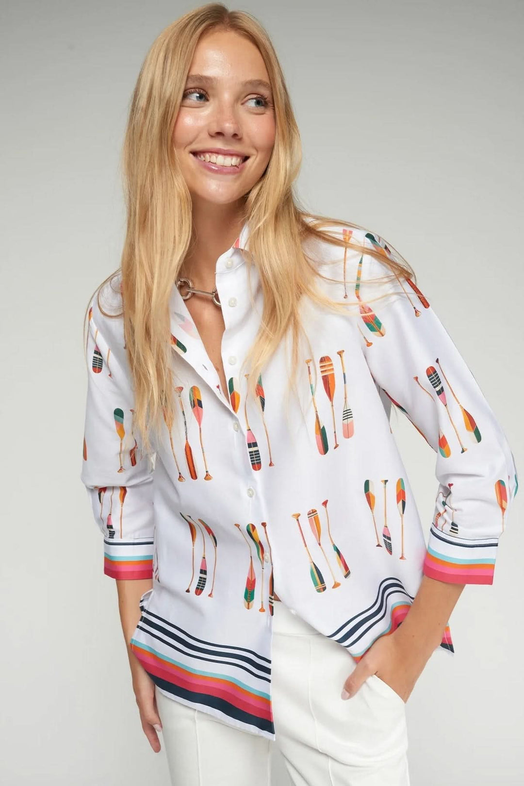 Femme portant une chemise imprimé pagaies avec des motifs colorés et manches longues, silhouette fluide, col classique et fermeture boutonnée.