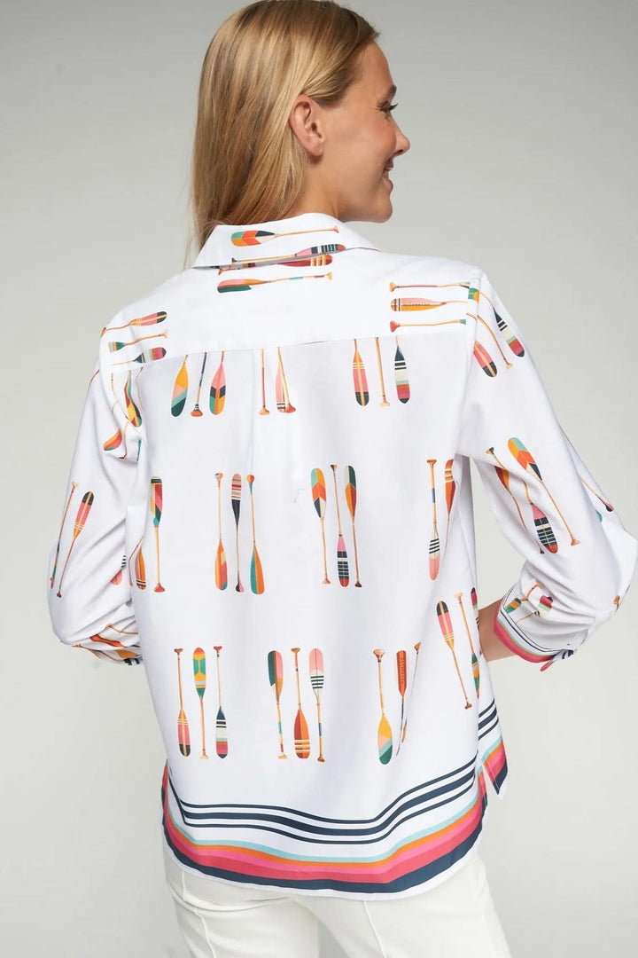 Femme portant une chemise imprimé pagaies au motif graphique vibrant, col chemise et bande contrastante moderne.