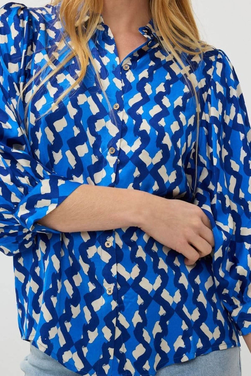 Chemise imprimée bleue satiné avec un motif abstrait et manches bouffantes, idéale pour un look décontracté.