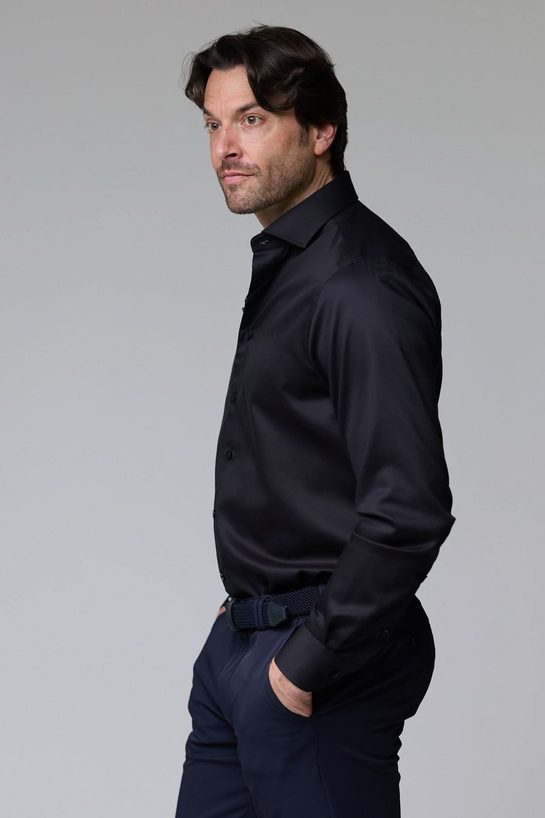 Homme portant une chemise habillée satinée noire avec coupe ajustée et col élégant pour un look sophistiqué et moderne.