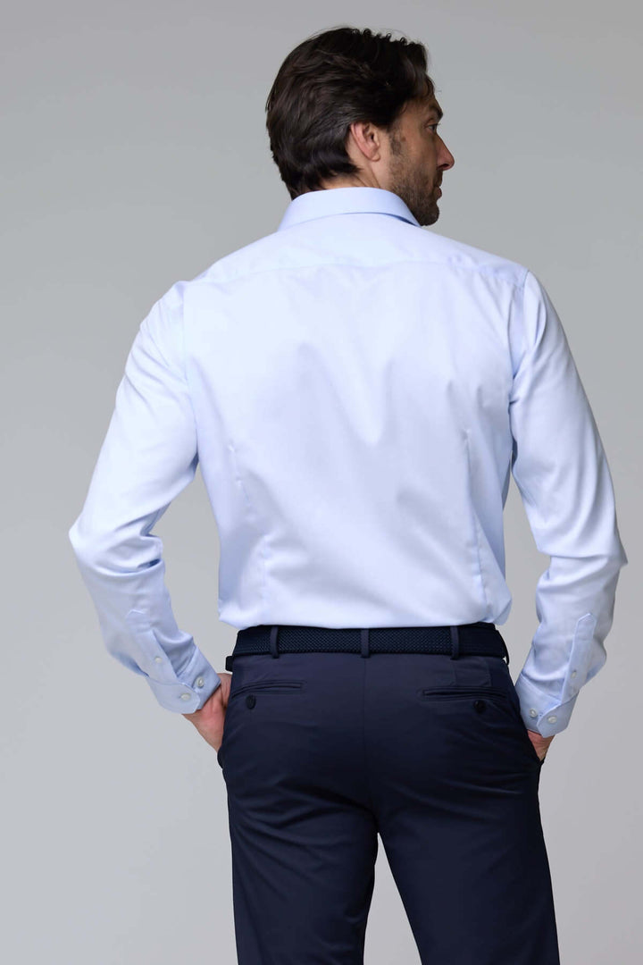 Homme vêtu de chemise habillée satinée à manches longues, vue de dos, montrant la texture lisse et l'éclat discret de la chemise.