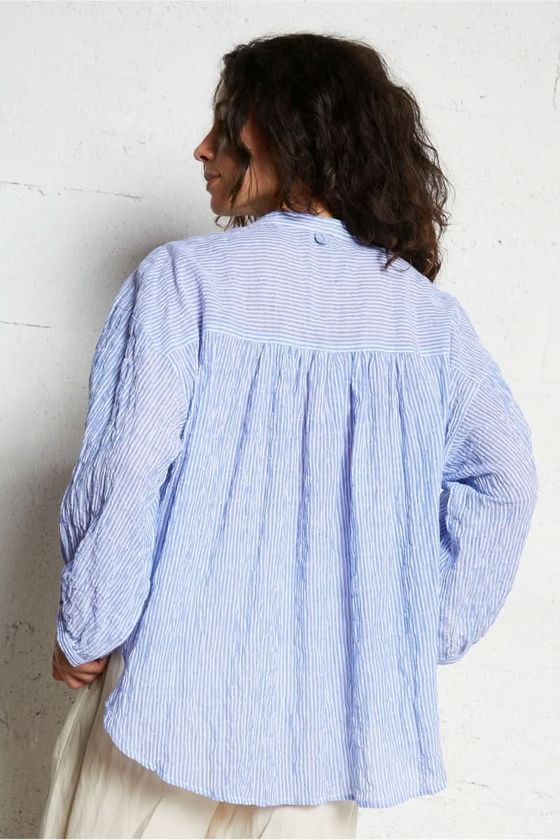 Femme portant une chemise intemporel bleue à rayures, vue de dos.