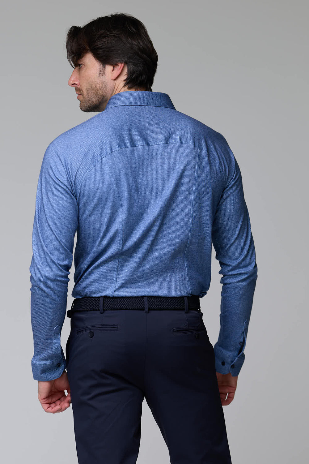 Chemise jersey texturé bleue à manches longues vue de dos, col structuré, portée par un homme, élégance moderne et confort décontracté.