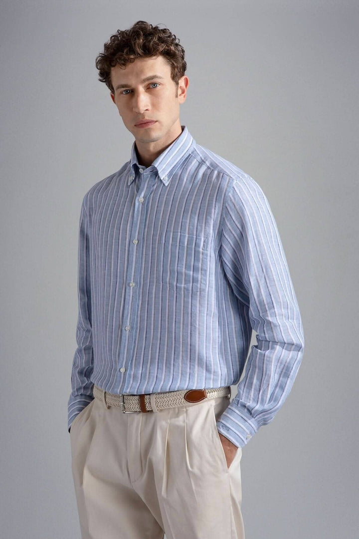 Chemise lignée élégante en lin avec des rayures bleues, portée par un homme en pantalon clair, style décontracté.