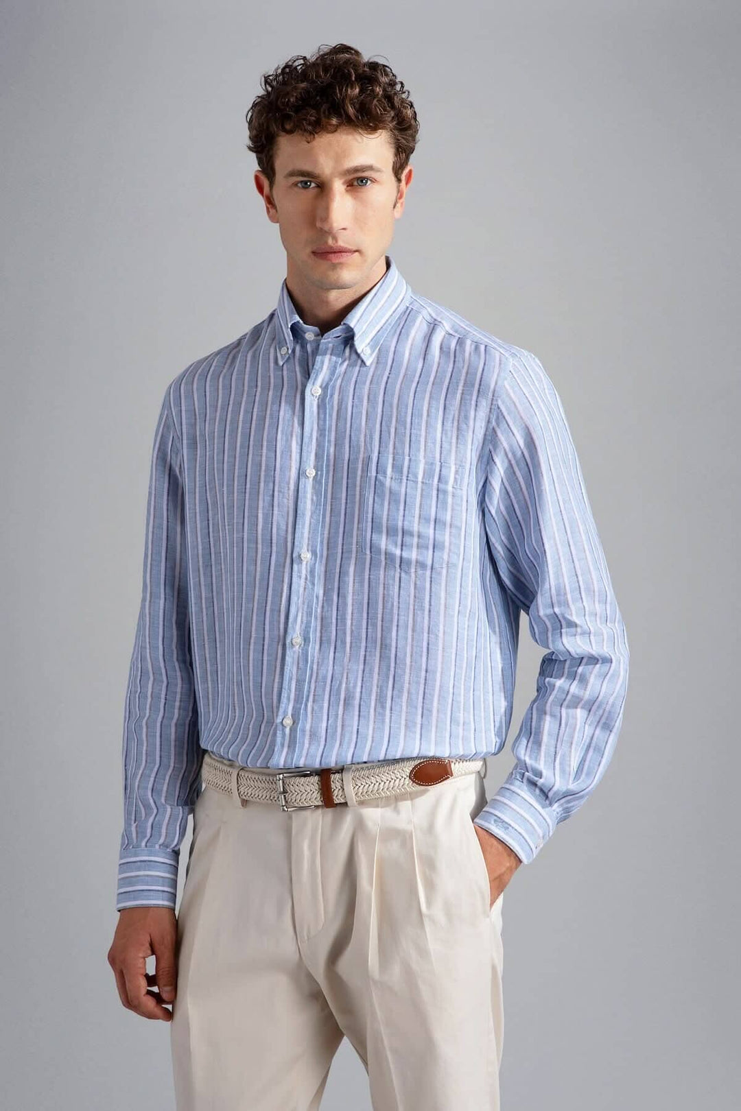 Chemise en lin à rayures bleues, élégante et décontractée, portée avec un pantalon clair.