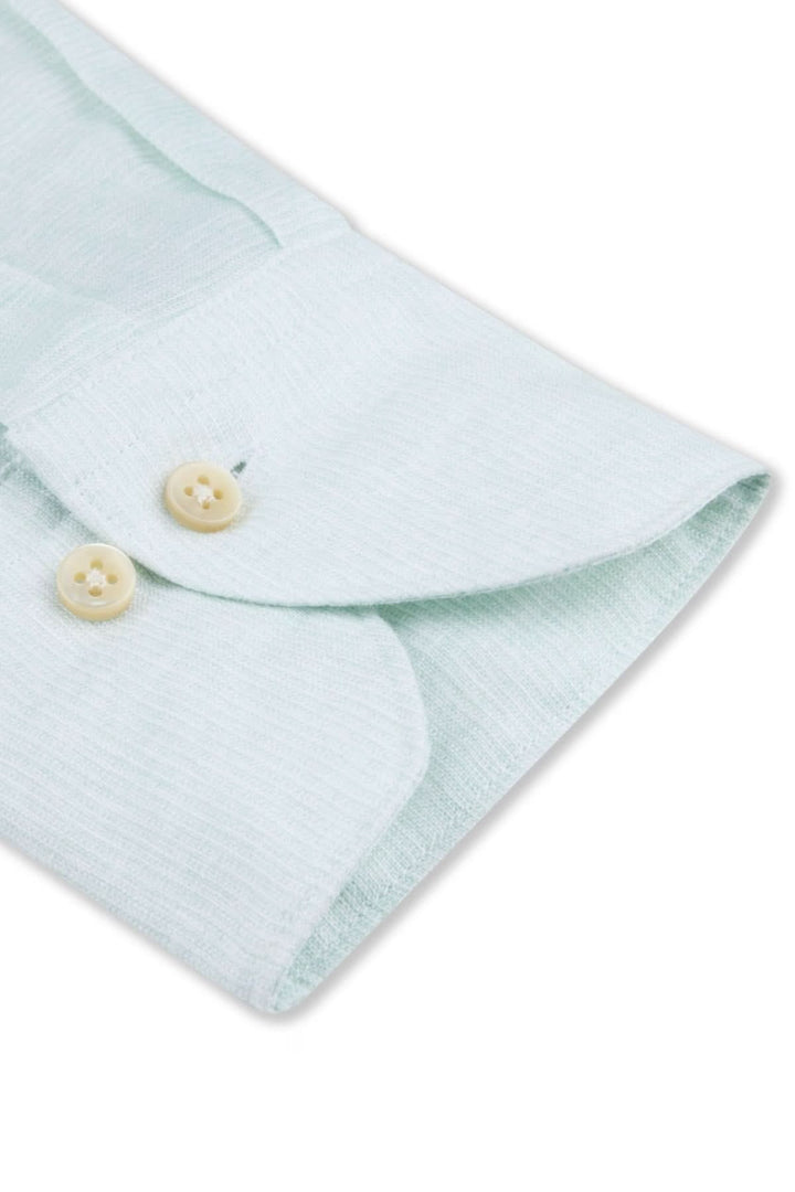 Détail de la chemise à manches longues en lin, avec boutons en nacre et tissu léger à texture linéaire.