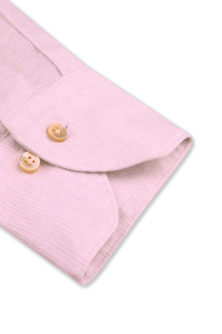 Détail d'une chemise à manches longues en lin avec col classique et boutons en nacre, coloris doux.