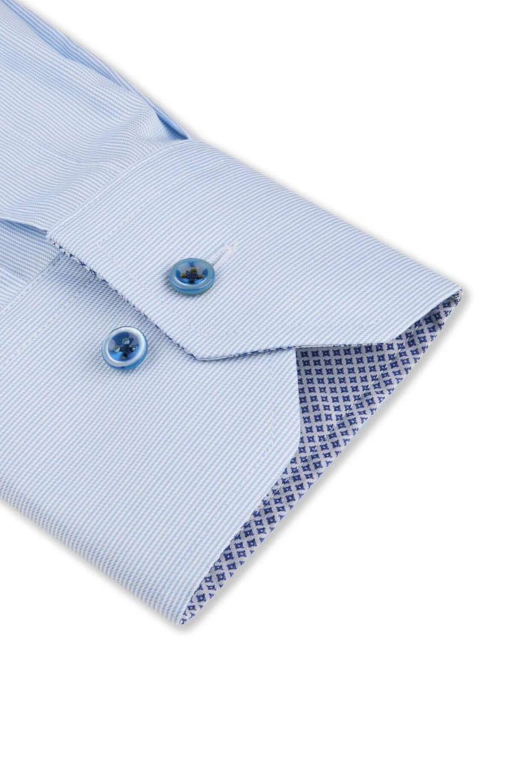Détail d'une chemise élégante à manches longues, col italien et poignets contrastés en bleu.