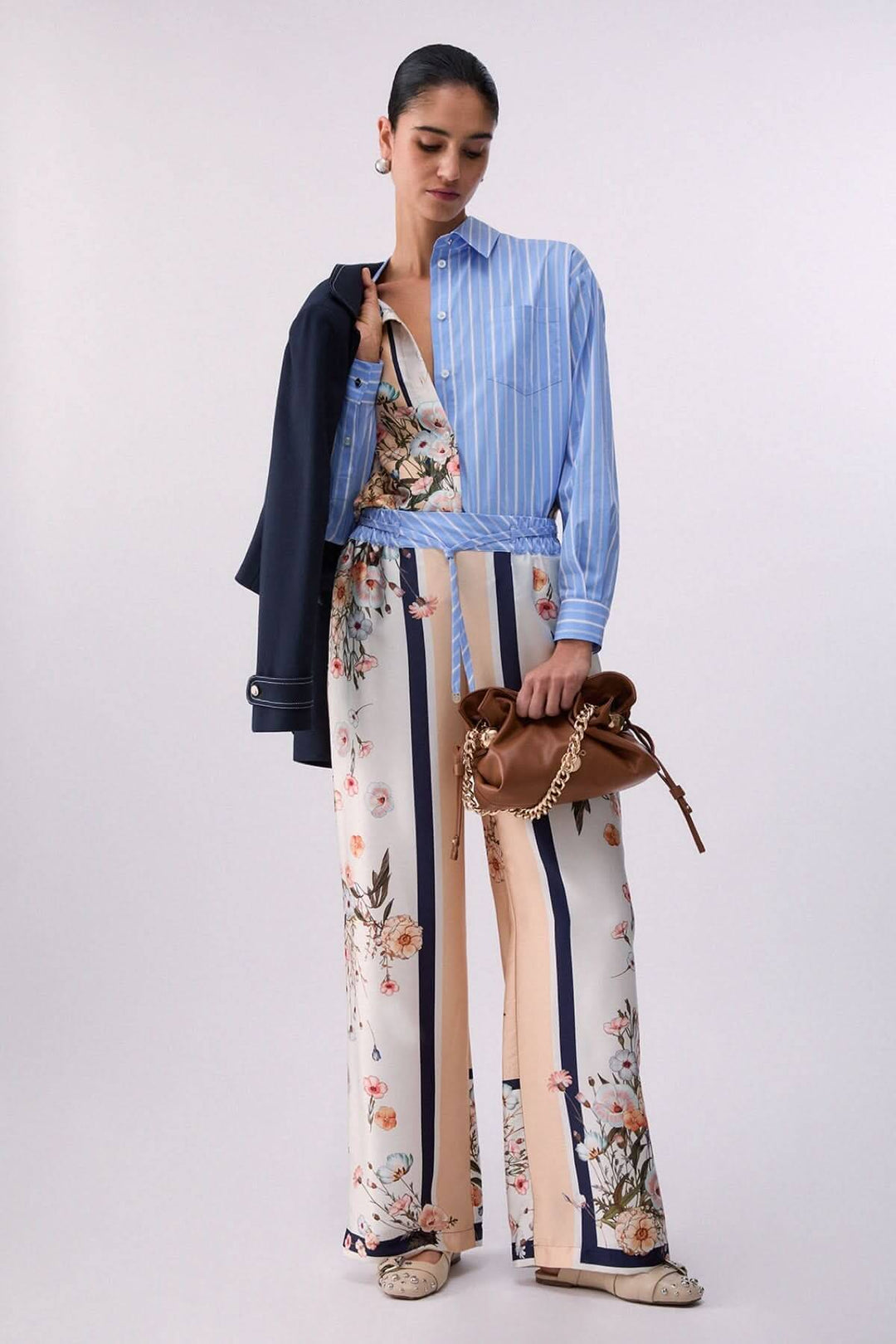 Chemise à manches longues avec motifs contrastés pour un style moderne et élégant. Femme posant avec une chemise rayée et pantalon floral.