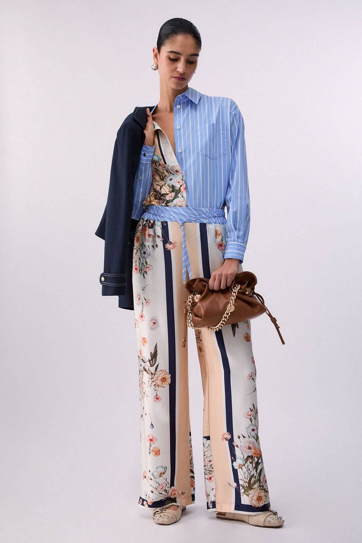Chemise à manches longues avec motifs contrastés pour un style moderne et élégant. Femme posant avec une chemise rayée et pantalon floral.