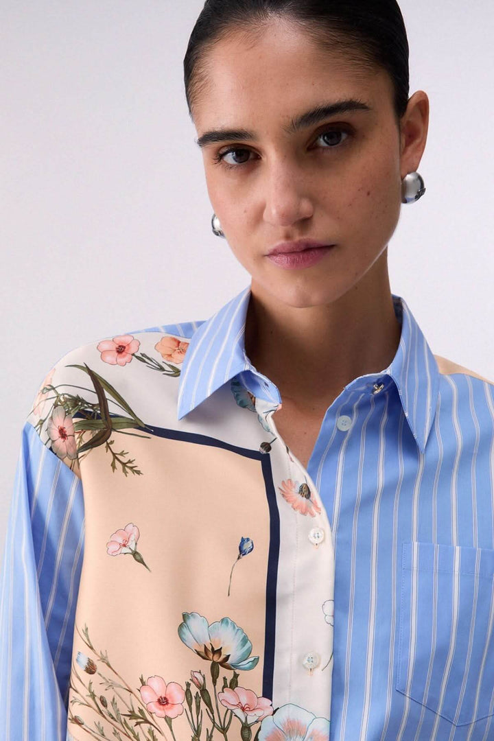 Chemise à manches longues avec motifs contrastés, femme portant une chemise à motifs floraux et rayures bleues élégantes.