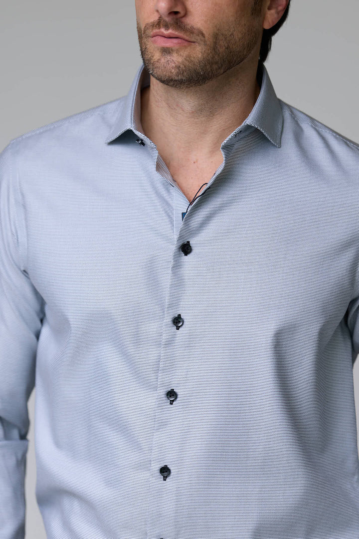 Homme portant une chemise à micro-motif texturé avec des boutons noirs, style élégant pour bureau ou occasion chic, coupe ajustée moderne.