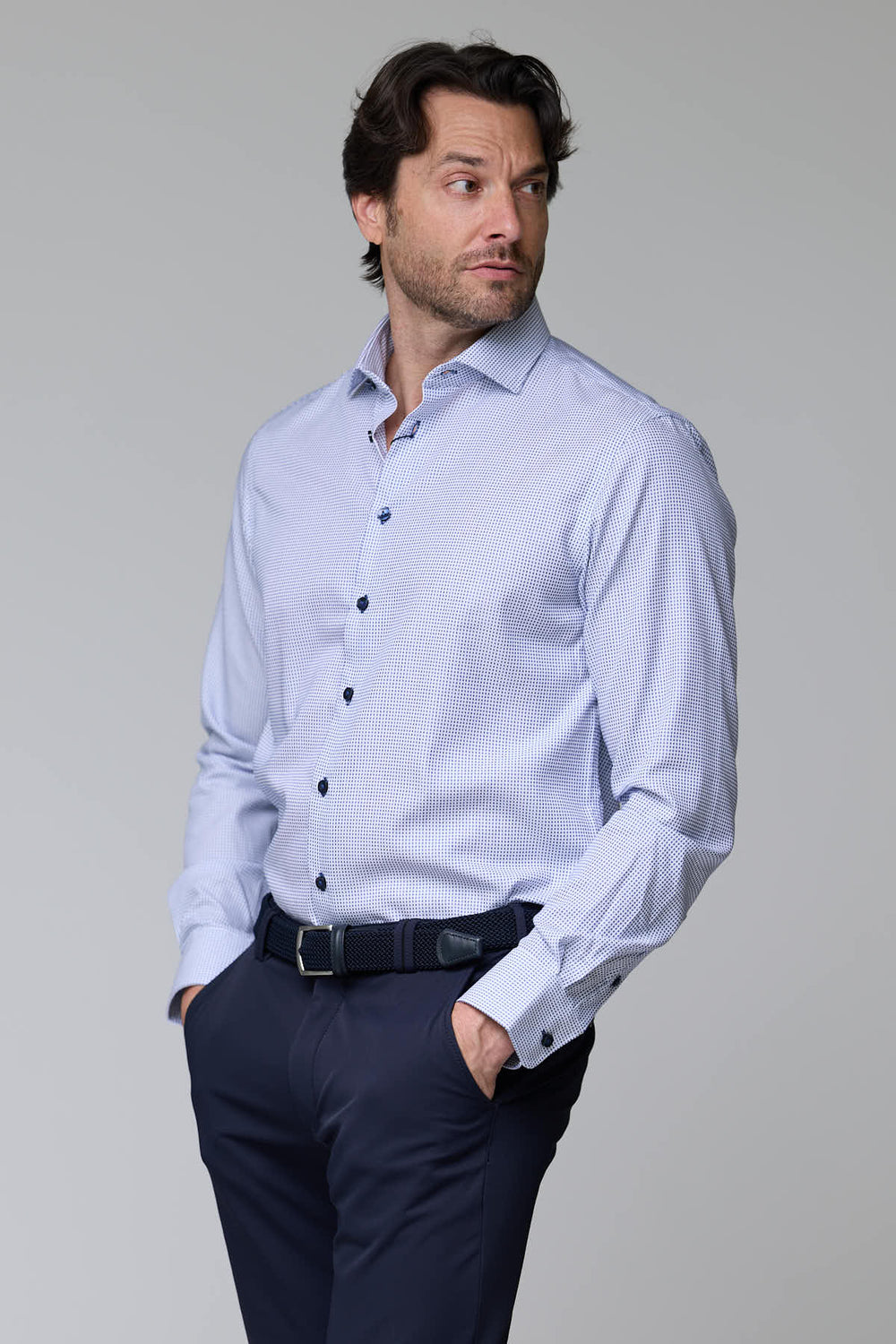 Homme portant une chemise à motif géométrique avec manches longues et col structuré, style élégant et moderne.