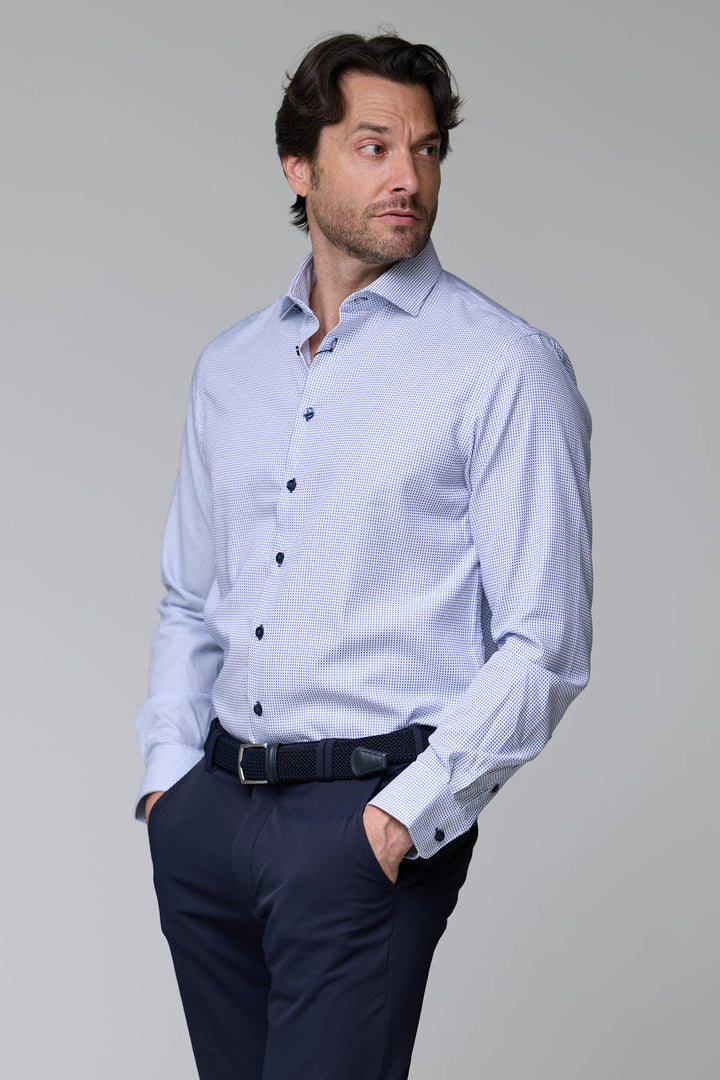 Homme portant une chemise à motif géométrique avec manches longues et col structuré, style élégant et moderne.