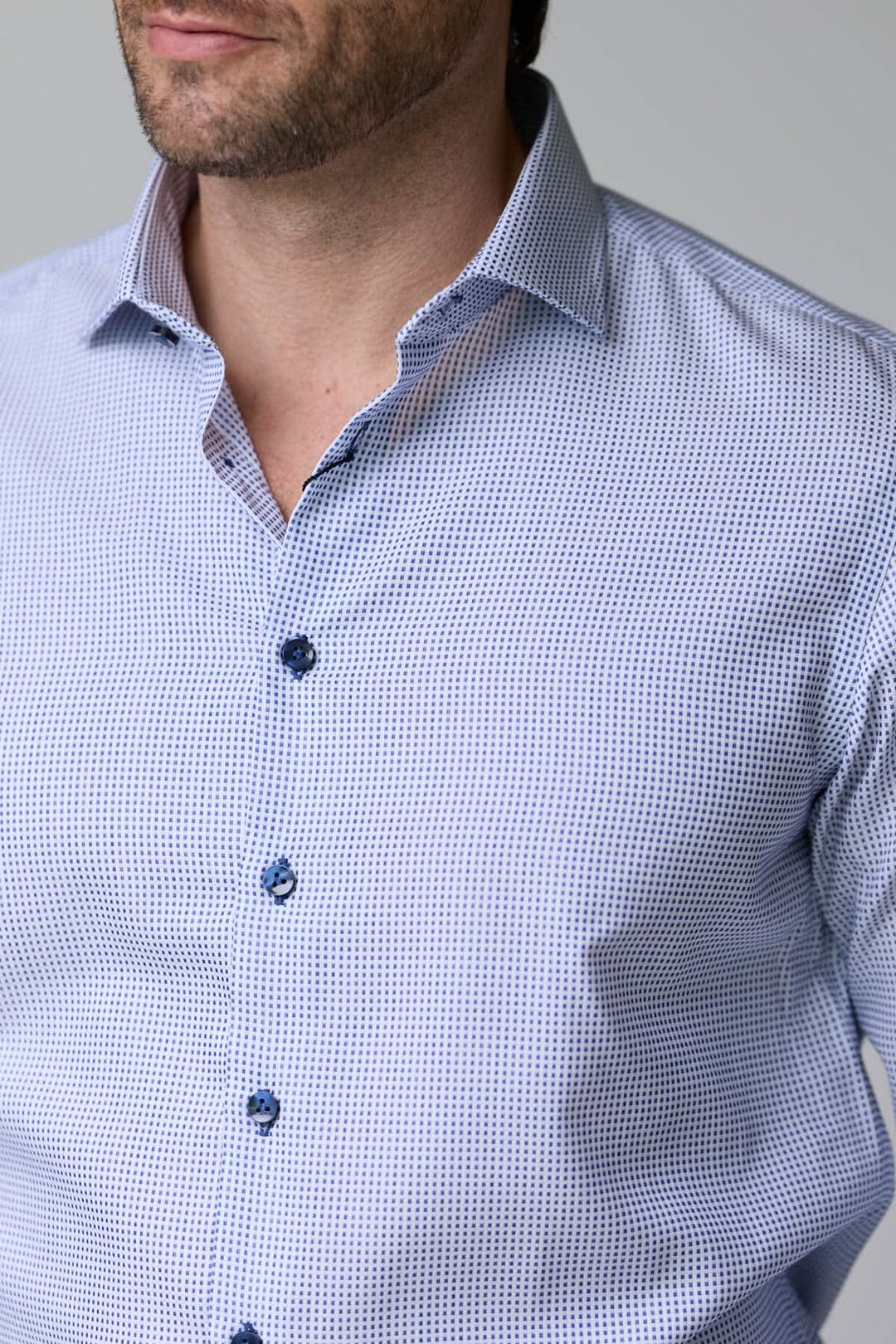 Homme portant une chemise à motif géométrique élégant avec boutons contrastants et col structuré pour un look moderne.