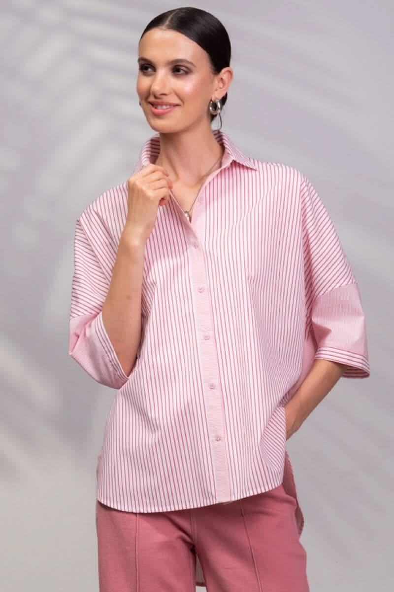Chemise rayée rose à manches 3/4, coupe oversize, chic et décontractée, portée avec un pantalon.