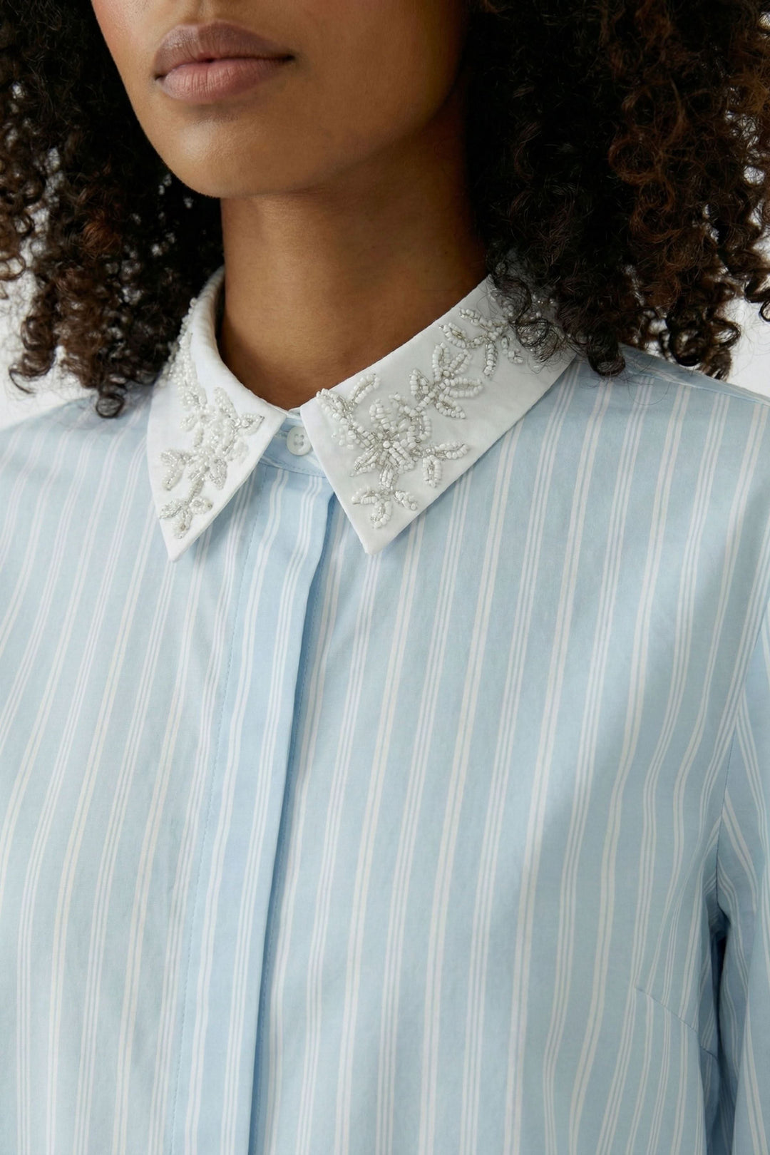 Chemise rayée à col brodé en gros plan montrant le col délicatement brodé et les rayures verticales élégantes.