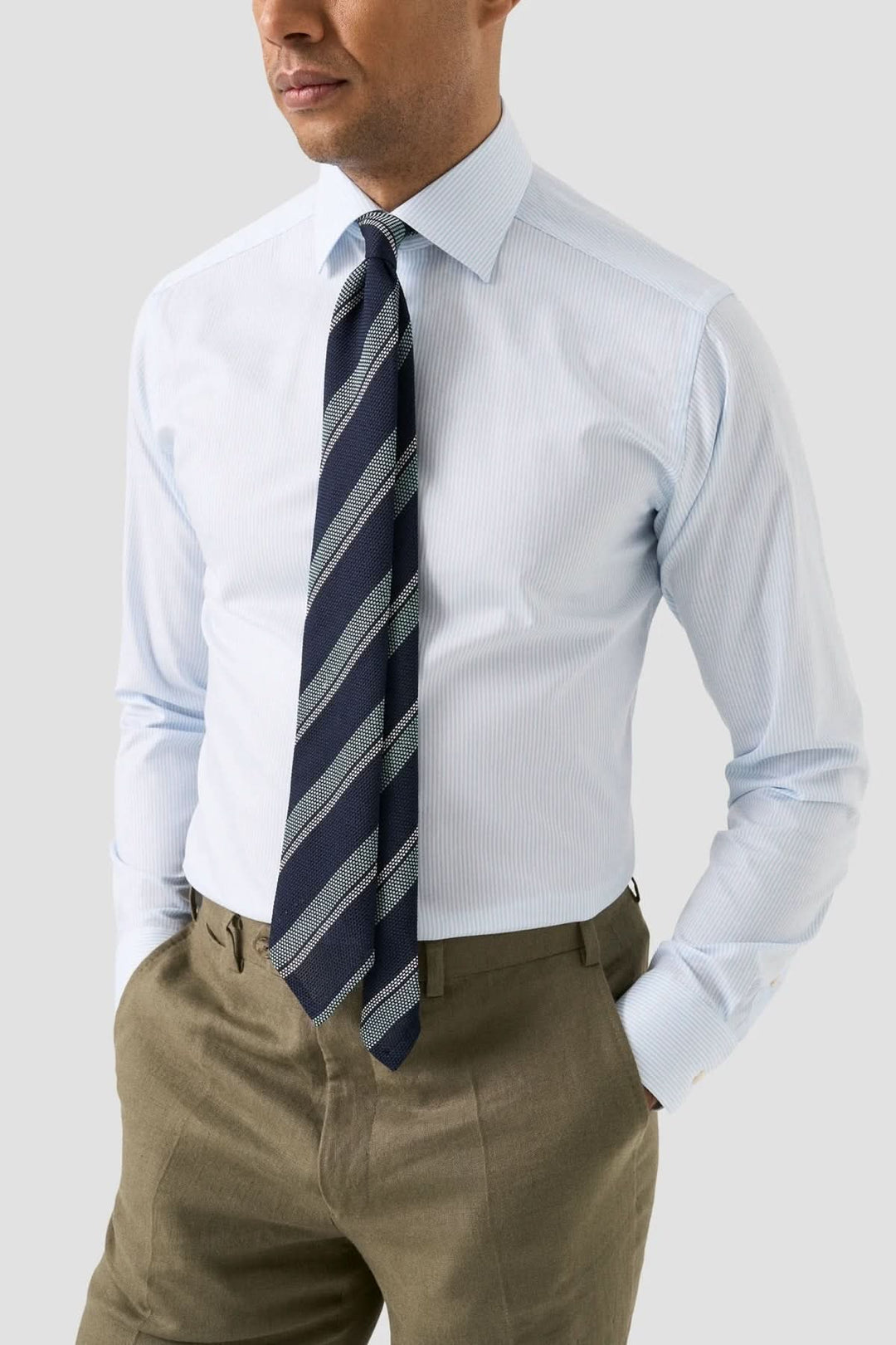 Homme portant une chemise rayée en coton et lyocell avec cravate, style professionnel élégant.