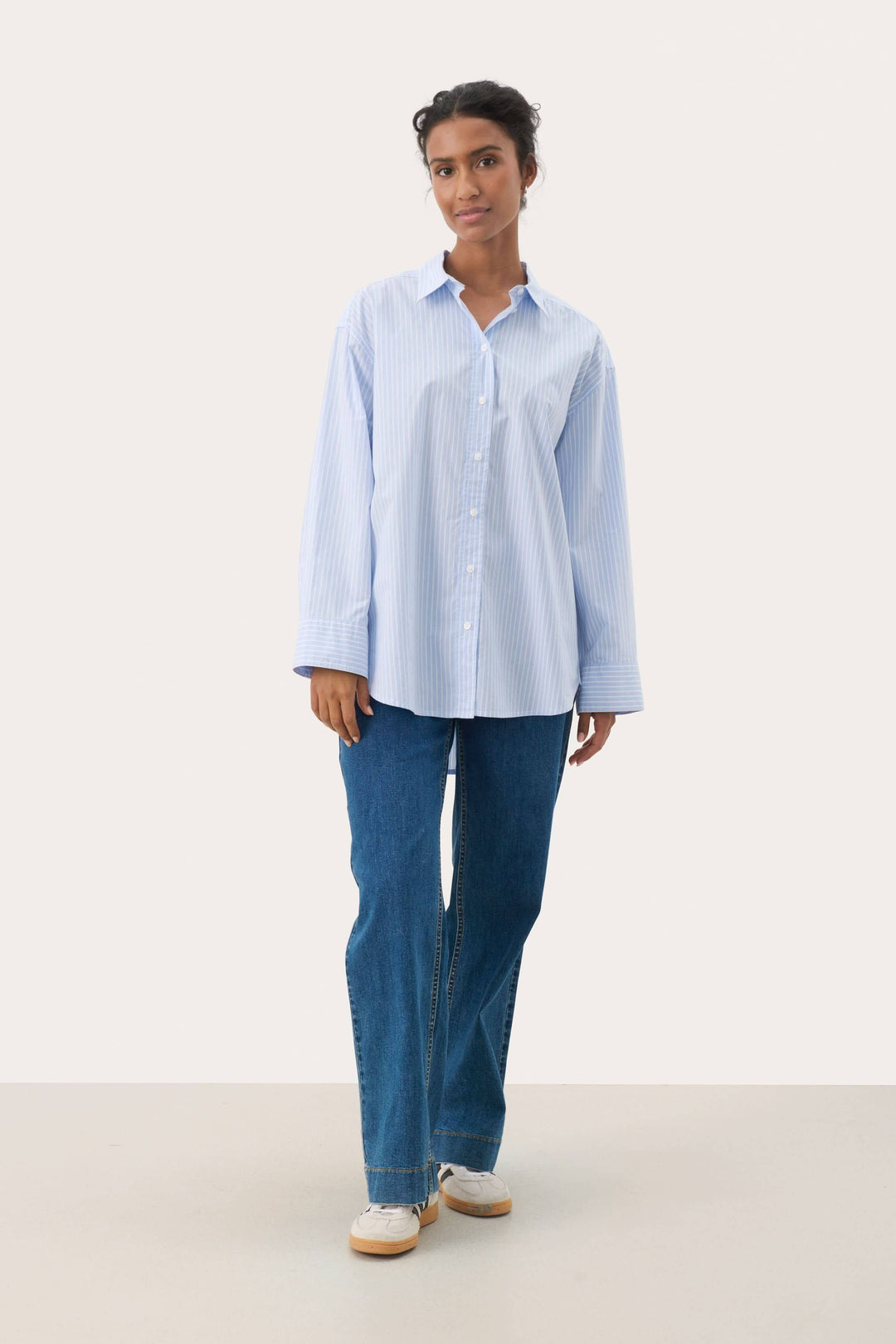 Femme portant chemise rayée Savanna ample avec col classique, manches longues, et jean droit, style chic et décontracté.