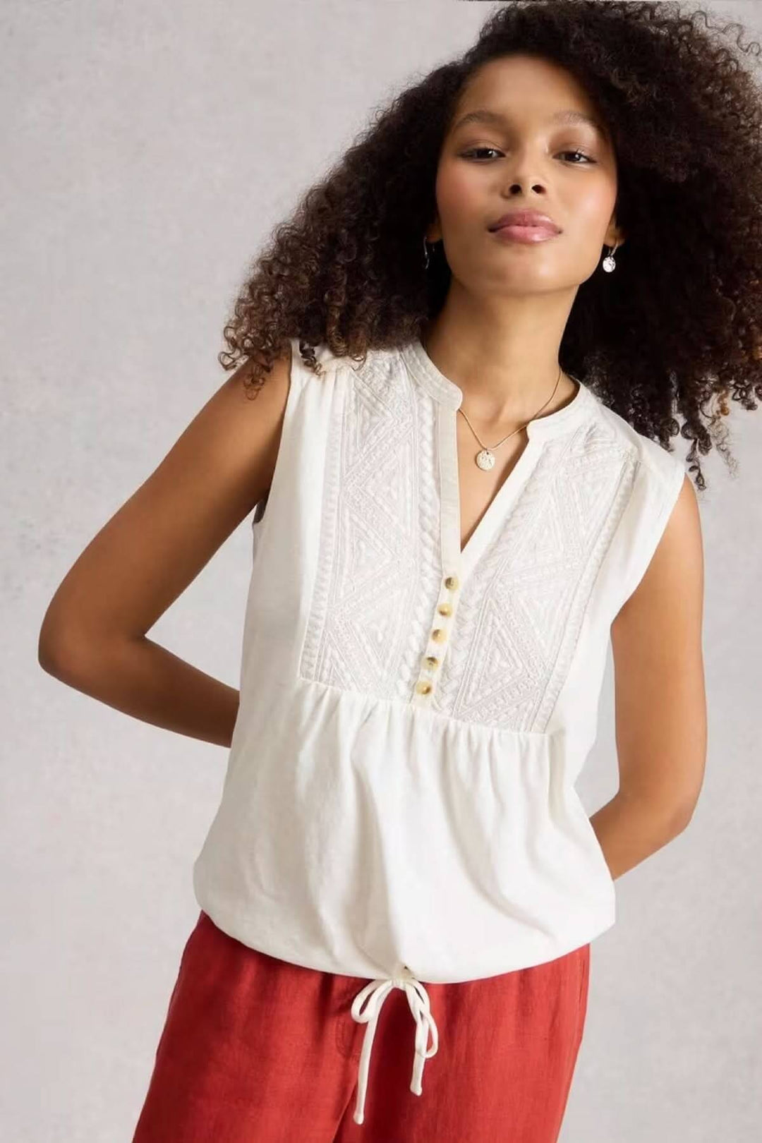Chemise sans manches Peony avec plastron brodé et encolure ouverte, portée par une femme, offrant une allure fluide et élégante.