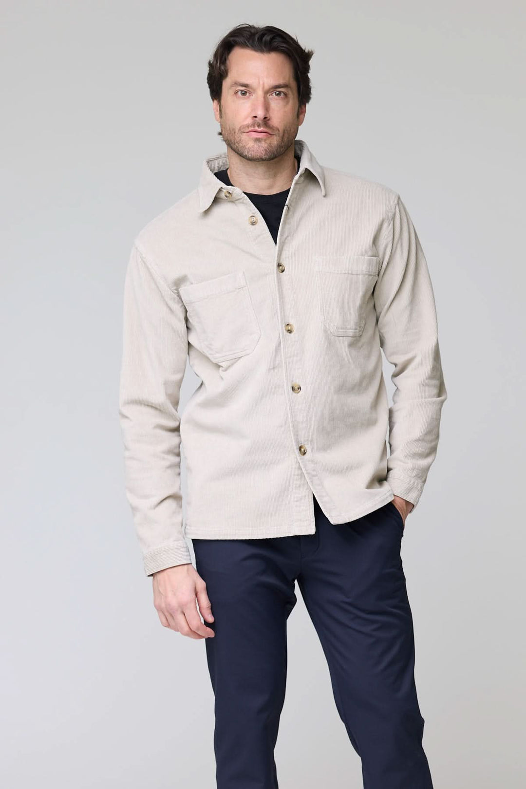 Homme portant une chemise sport en velours côtelé style surchemise beige avec poches plaquées, idéale pour un look décontracté.