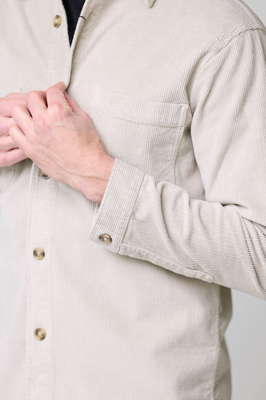 Homme portant une chemise sport en velours côtelé style surchemise avec boutons contrastants, vue de près sur les détails.