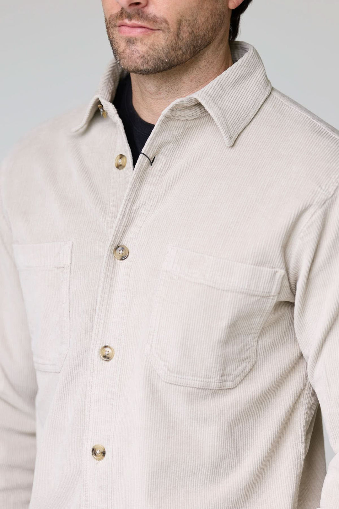 Homme portant une chemise sport en velours côtelé style surchemise beige avec poches plaquées et boutons contrastants.