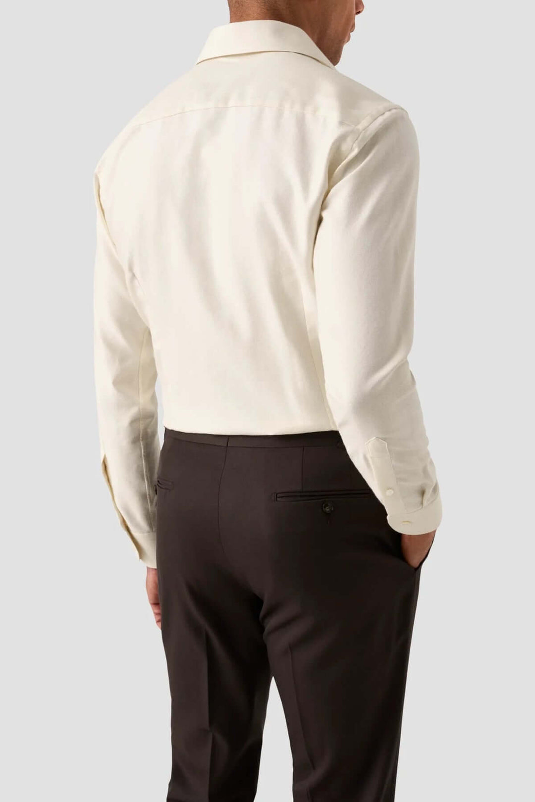 Chemise unie en coton beige vue de dos avec pantalon noir, style élégant et moderne pour occasions spéciales.
