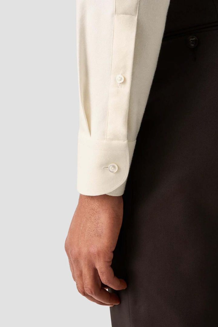 Man’s hand wearing an elegant cream cotton shirt with structured cuffs.