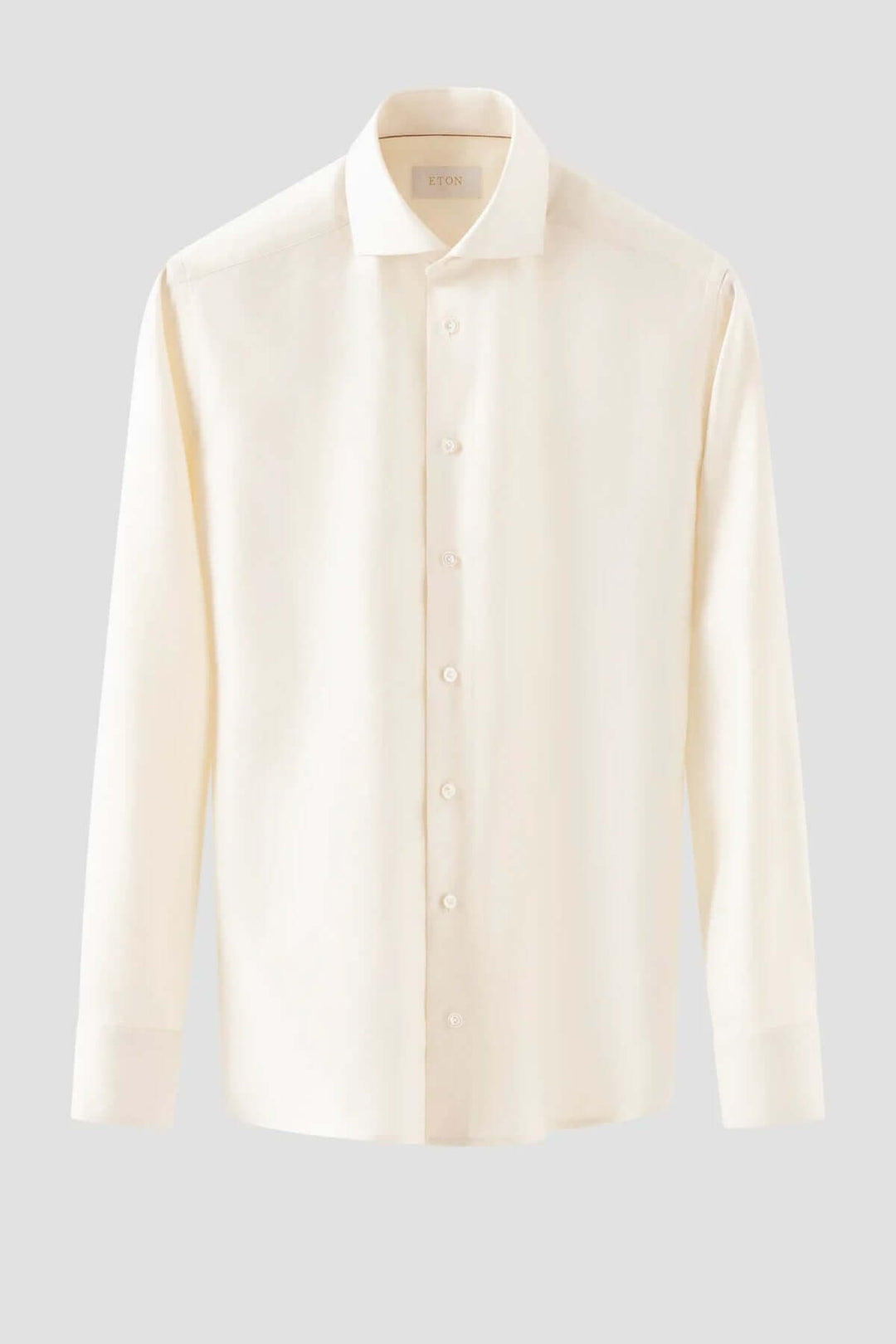 Chemise en coton élégante de couleur crème avec col classique et poignets simples, parfaite pour occasions spéciales.