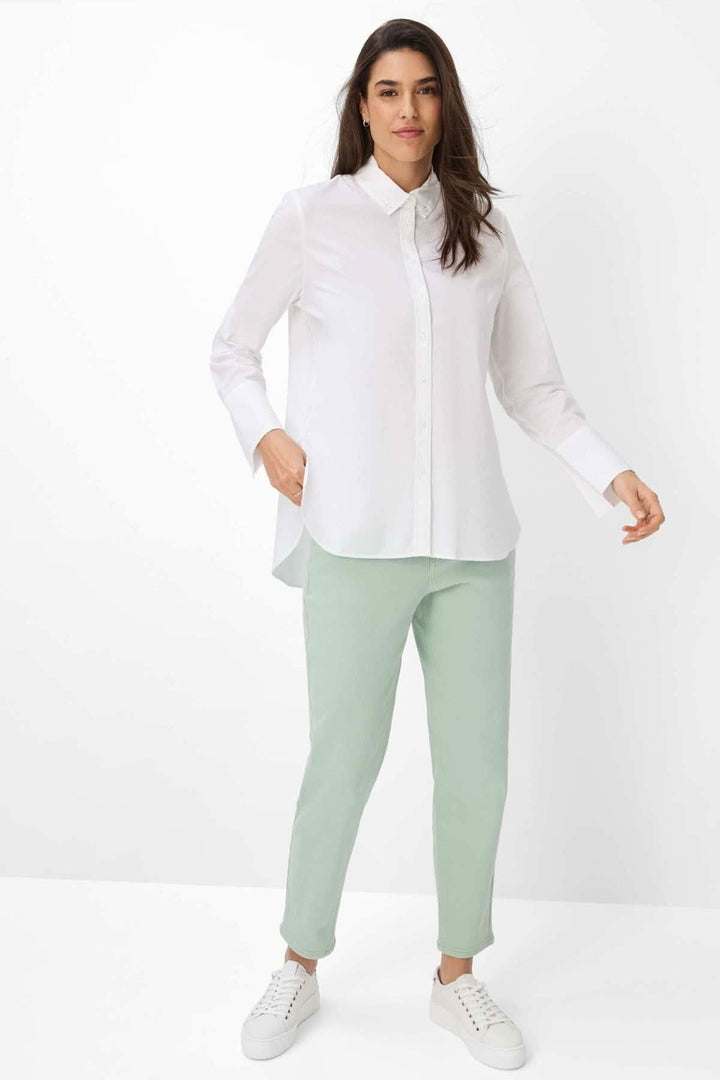 Chemisier classique VIKI en blanc, porté avec un pantalon vert menthe et des baskets blanches, style élégant et moderne.