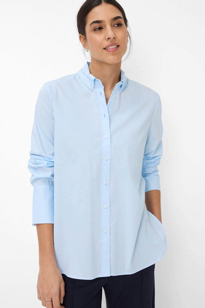 Chemisier classique VIKI en bleu clair avec col boutonné et manches longues, idéal pour un look moderne et élégant.
