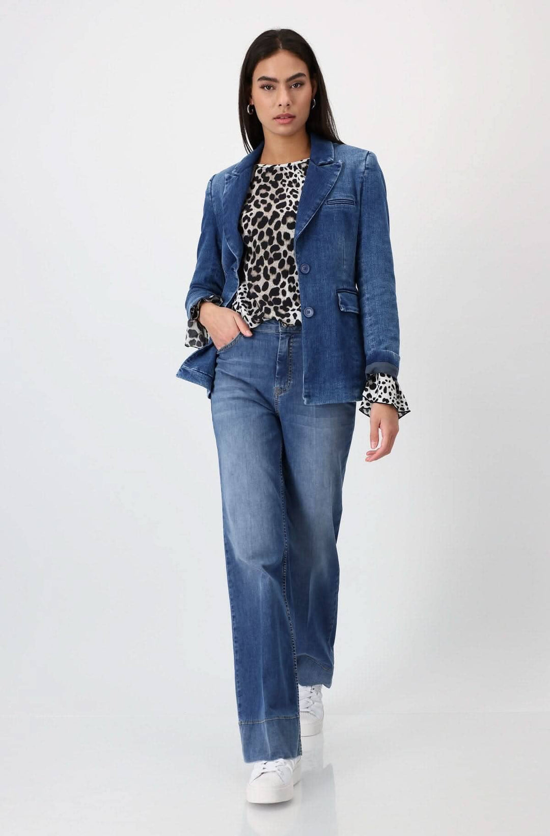 Femme portant un chemisier imprimé léopard avec un blazer en denim et un pantalon décontracté.