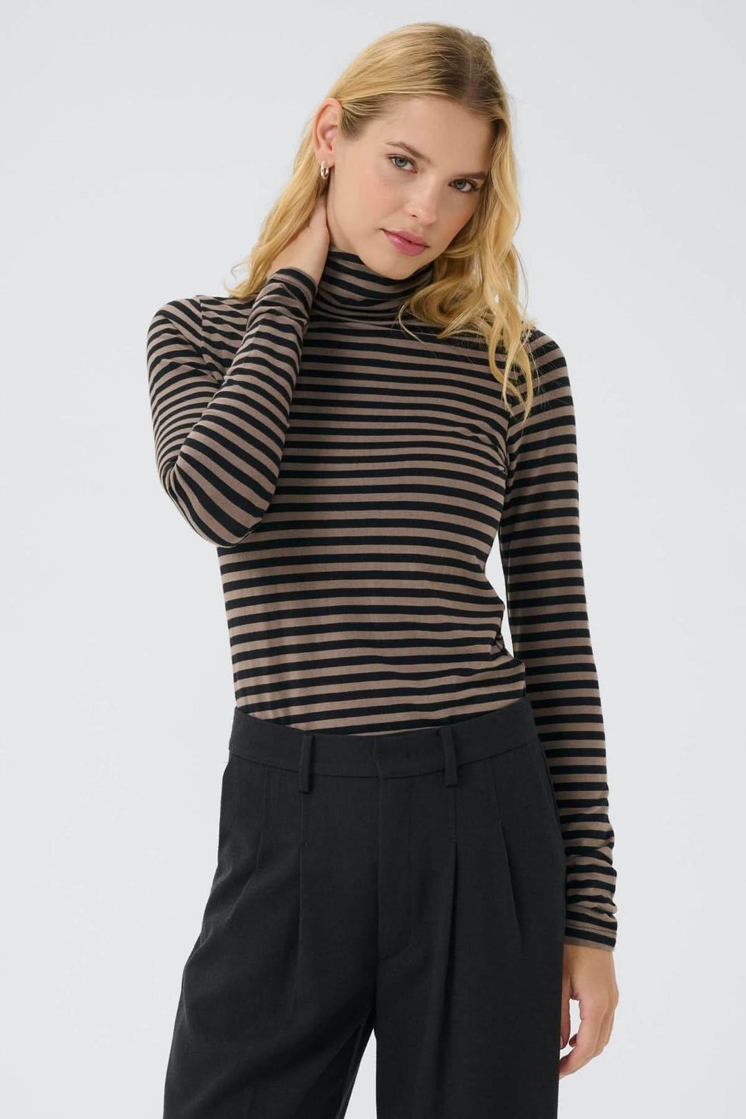 Femme portant un col roulé Efinas avec rayures noires et marron, manches longues, coupe ajustée, élégant et intemporel.