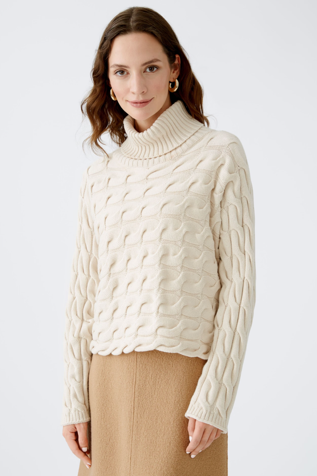 Col roulé en tricot torsadé beige, manches longues, idéal pour un look chic et élégant en hiver.
