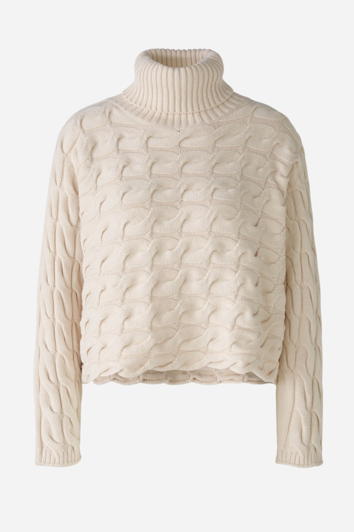Col roulé en tricot torsadé crème, à manches longues, idéal pour des tenues d'hiver élégantes.